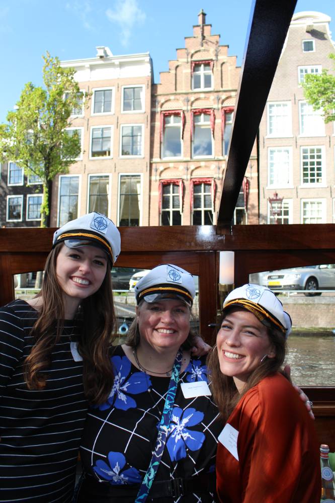 three global lakers smile in captains hats on boat